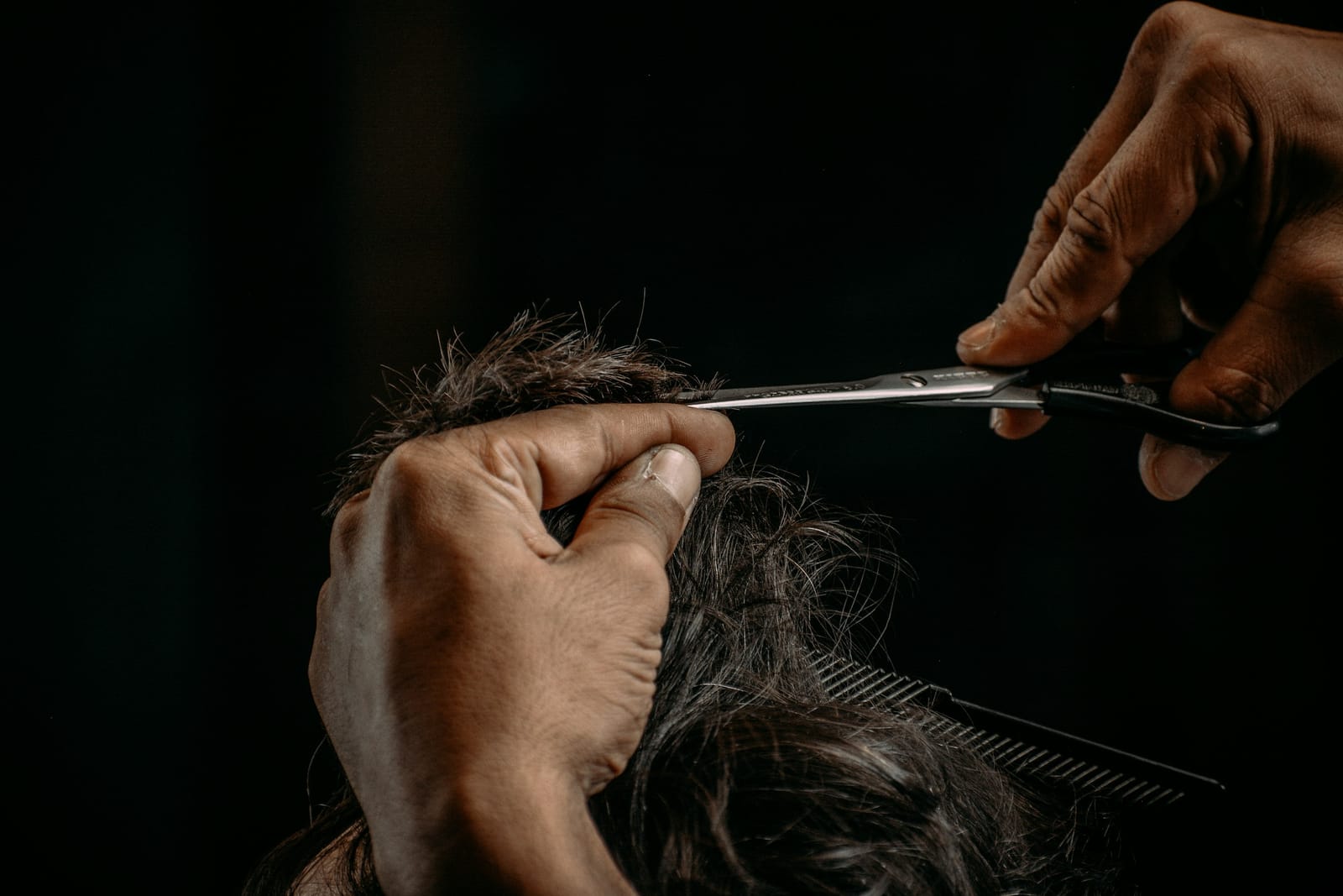 Mani che tagliano i capelli con forbici in acciaio